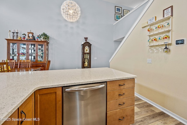 kitchen featuring light hardwood / wood-style flooring, dishwasher, and light stone countertops