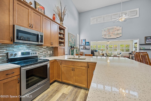 kitchen with sink, backsplash, light stone countertops, and stainless steel appliances