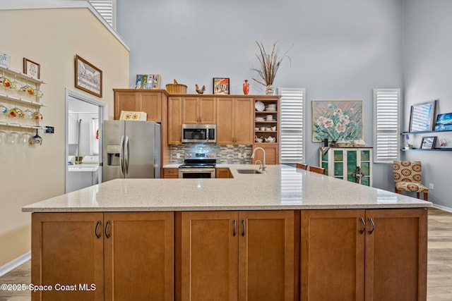 kitchen featuring light hardwood / wood-style flooring, sink, tasteful backsplash, light stone counters, and stainless steel appliances