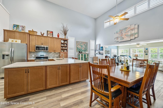 kitchen featuring a towering ceiling, a kitchen island with sink, appliances with stainless steel finishes, and backsplash