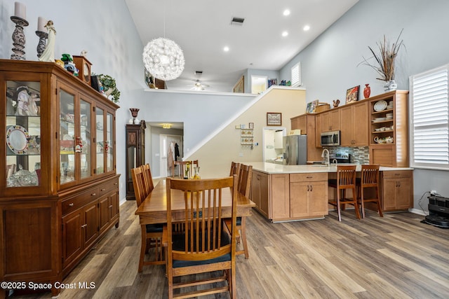 dining space featuring plenty of natural light, hardwood / wood-style flooring, a towering ceiling, and ceiling fan