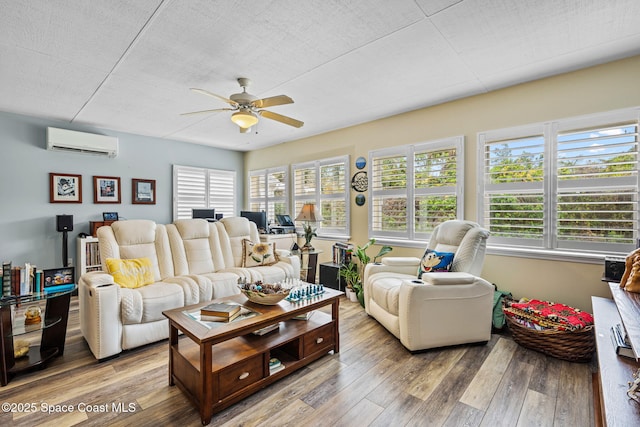 living room with ceiling fan, wood-type flooring, and a wall unit AC