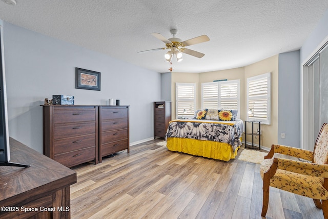 bedroom featuring light wood-type flooring, a textured ceiling, a closet, and ceiling fan