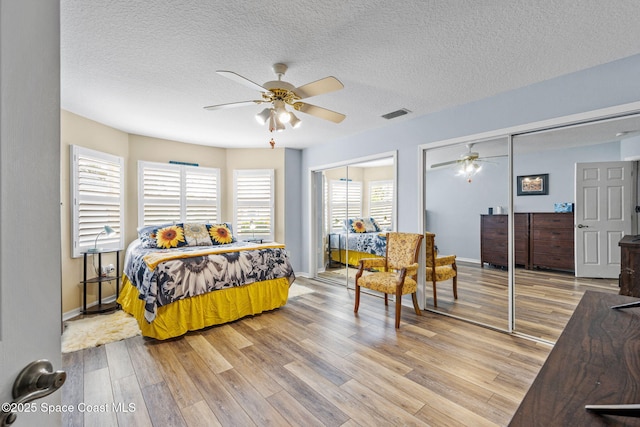 bedroom with ceiling fan, wood-type flooring, and a textured ceiling