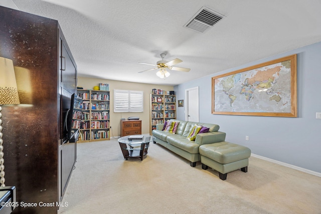 carpeted living room with a textured ceiling and ceiling fan