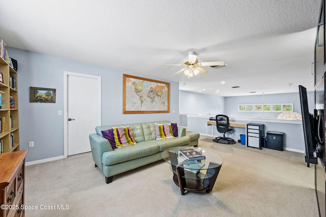 living room with a textured ceiling, light colored carpet, ceiling fan, and built in desk