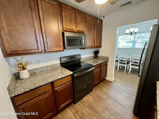 kitchen with light stone countertops, decorative light fixtures, ceiling fan with notable chandelier, and appliances with stainless steel finishes