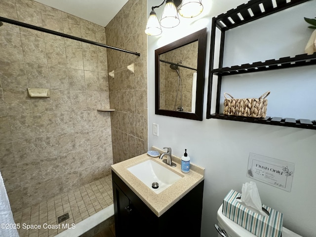 bathroom with tiled shower, vanity, and toilet