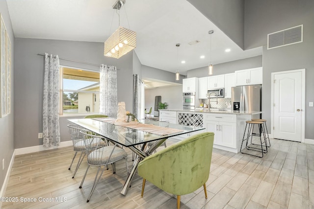 dining space featuring sink and lofted ceiling