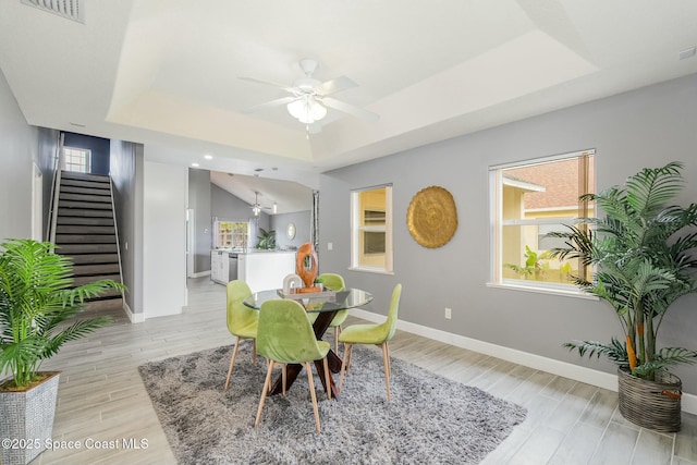 dining room featuring light hardwood / wood-style floors, ceiling fan, and a tray ceiling