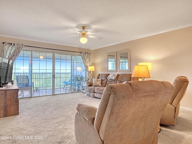 carpeted living room featuring a textured ceiling, ceiling fan, and ornamental molding