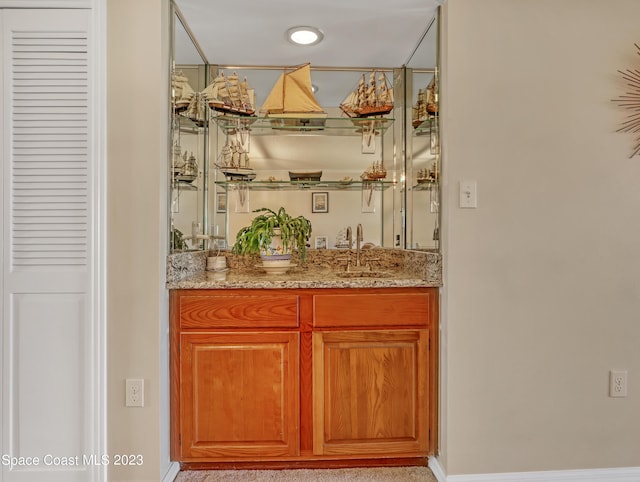 bar with light stone countertops and sink