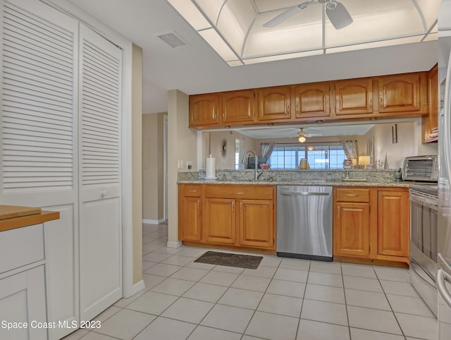 kitchen with dishwasher, light tile patterned flooring, light stone countertops, and sink