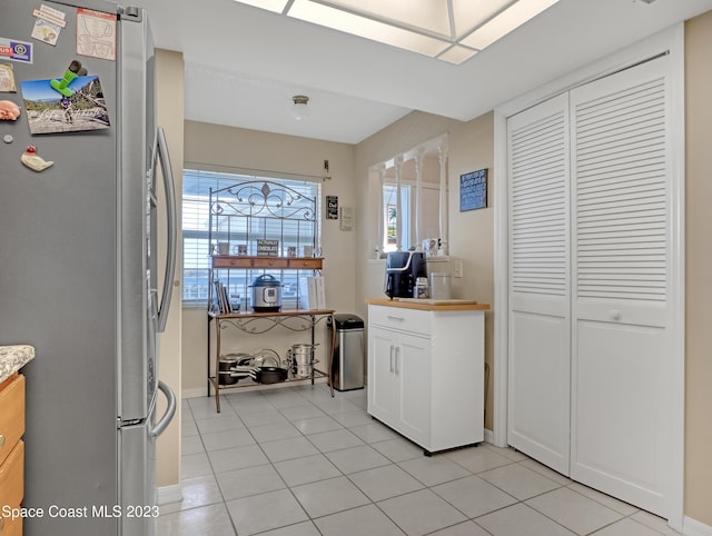 kitchen with stainless steel fridge, white cabinetry, plenty of natural light, and light tile patterned flooring