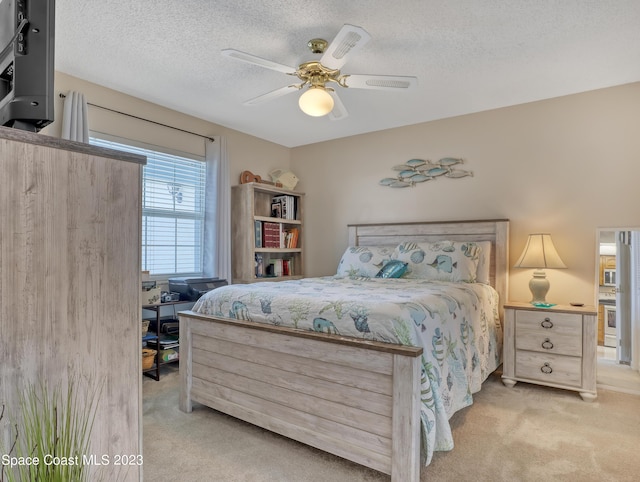 bedroom with a textured ceiling, light colored carpet, and ceiling fan