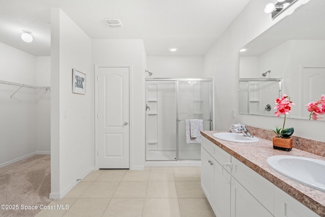 bathroom featuring a textured ceiling, walk in shower, tile patterned floors, and vanity