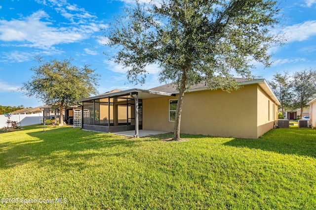 back of property with a yard and central AC