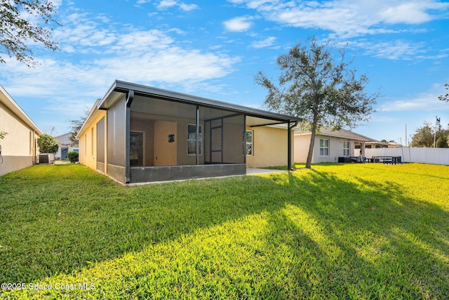 back of property featuring a sunroom, a yard, and central AC