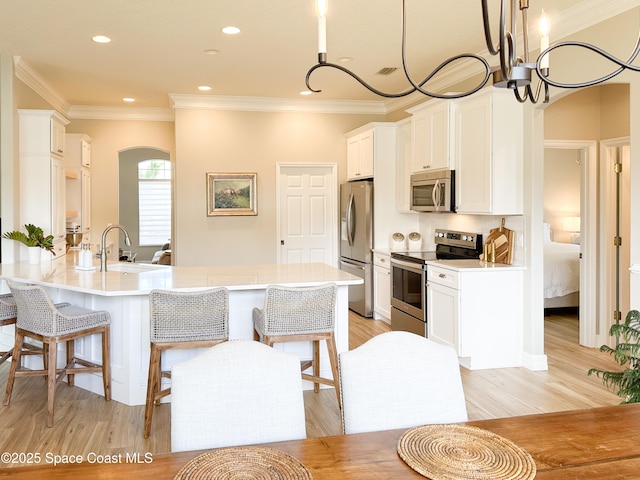 kitchen with stainless steel appliances, decorative light fixtures, sink, and white cabinets