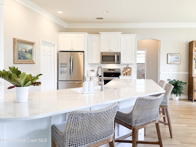 kitchen featuring stainless steel appliances, a breakfast bar, light wood-type flooring, and white cabinets