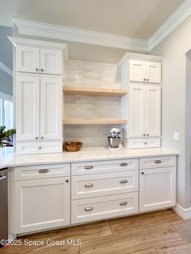 bar with backsplash, ornamental molding, light hardwood / wood-style flooring, and white cabinets