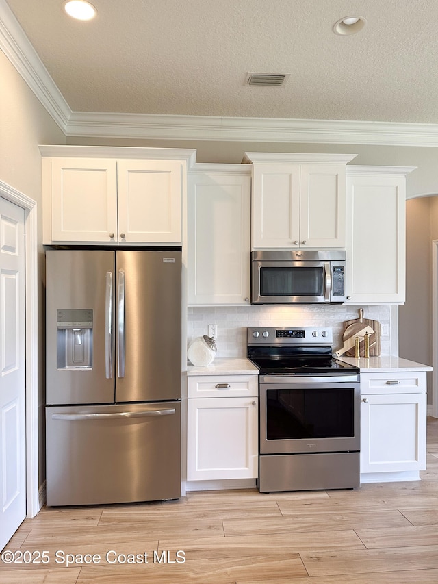 kitchen featuring stainless steel appliances, light wood-type flooring, decorative backsplash, and white cabinets