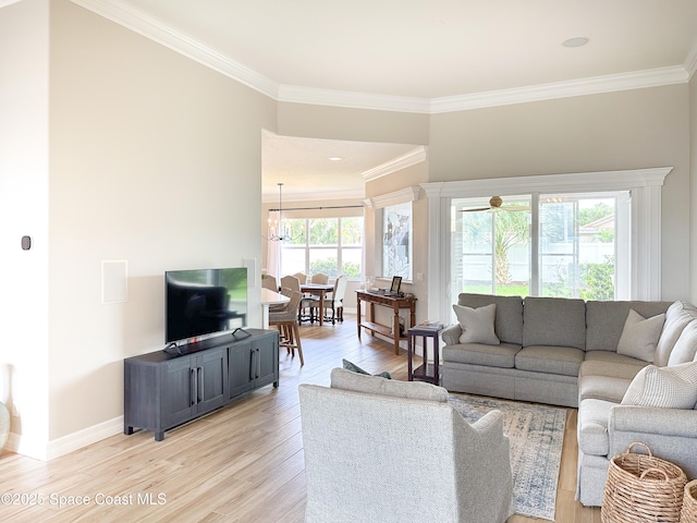 living room with ornamental molding, a notable chandelier, and light wood-type flooring