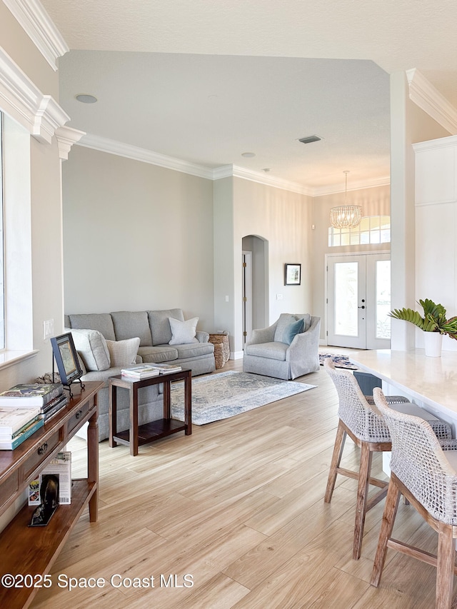 living room with crown molding, a notable chandelier, and light wood-type flooring