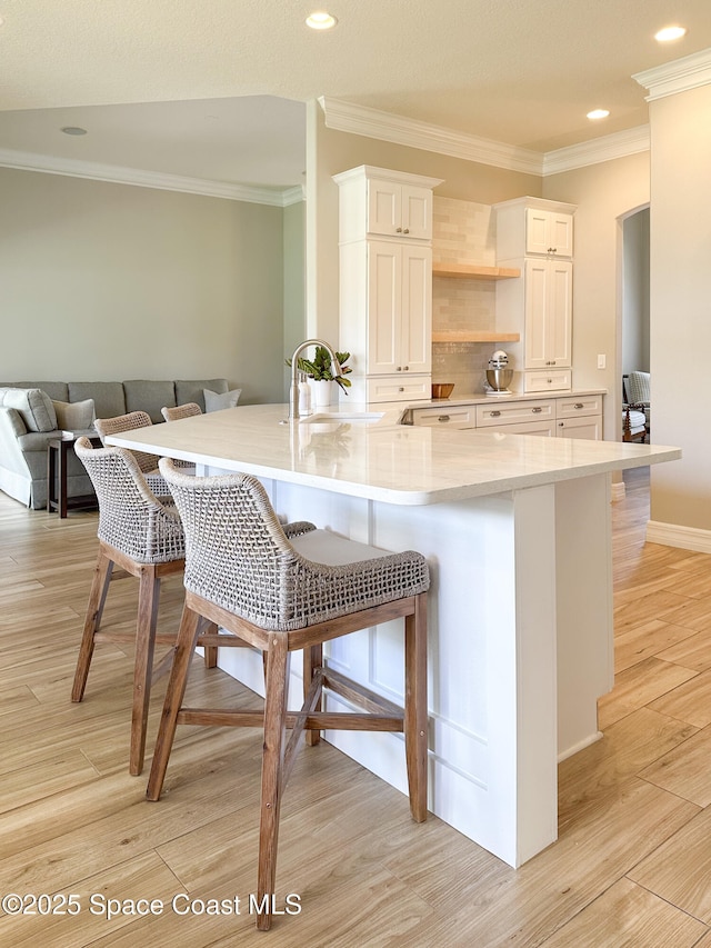 kitchen featuring white cabinetry, sink, a kitchen bar, kitchen peninsula, and light wood-type flooring