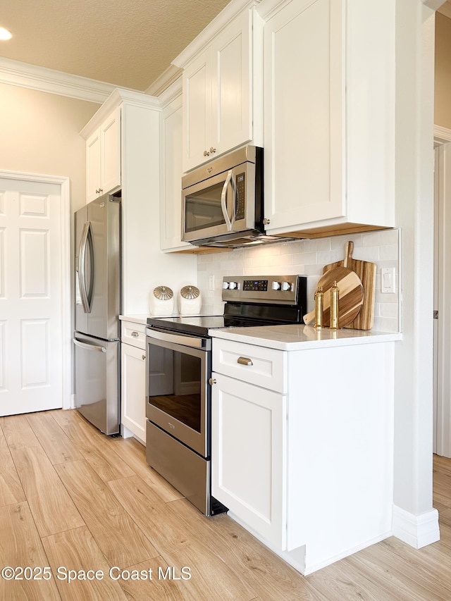 kitchen with white cabinetry, light hardwood / wood-style flooring, stainless steel appliances, and tasteful backsplash