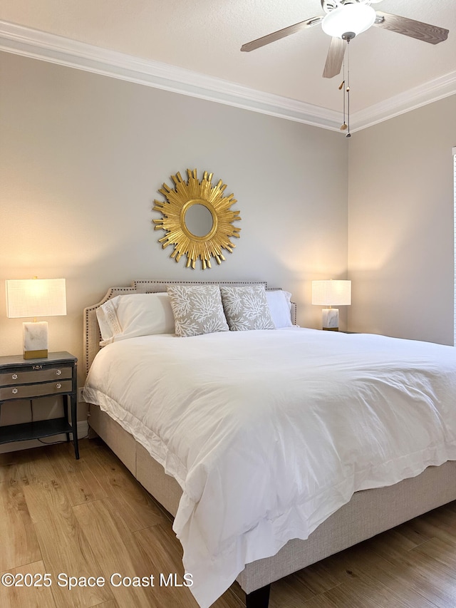 bedroom with crown molding, ceiling fan, and wood-type flooring