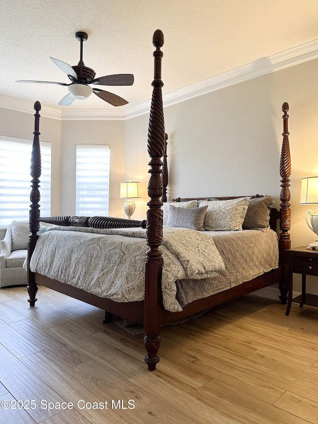 bedroom with hardwood / wood-style floors, crown molding, and ceiling fan