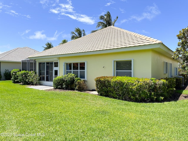 rear view of property with a lawn and a sunroom