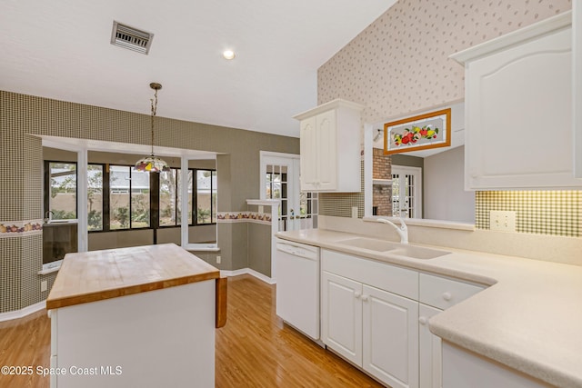 kitchen featuring pendant lighting, sink, white dishwasher, white cabinets, and kitchen peninsula