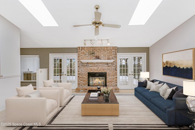 living room featuring vaulted ceiling, ceiling fan, a fireplace, and french doors