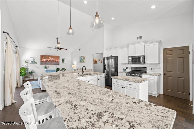 kitchen featuring a large island, sink, stainless steel appliances, tasteful backsplash, and pendant lighting