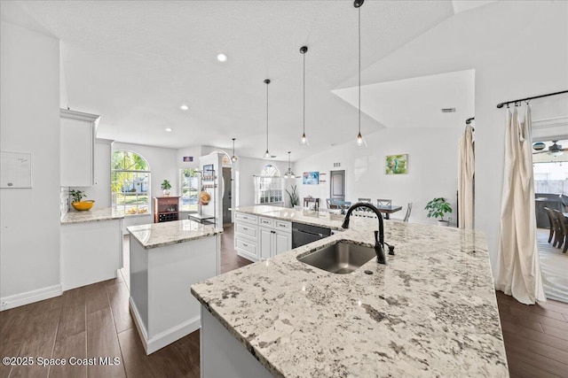 kitchen with light stone countertops, a large island, sink, dishwasher, and hanging light fixtures