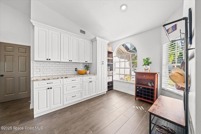 kitchen with backsplash, white cabinets, and vaulted ceiling