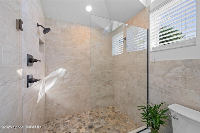 bathroom with a tile shower and toilet