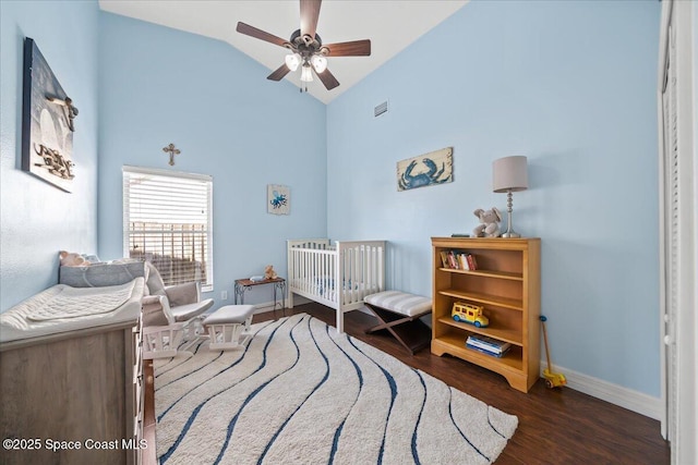 bedroom featuring a nursery area, dark wood-type flooring, ceiling fan, and lofted ceiling