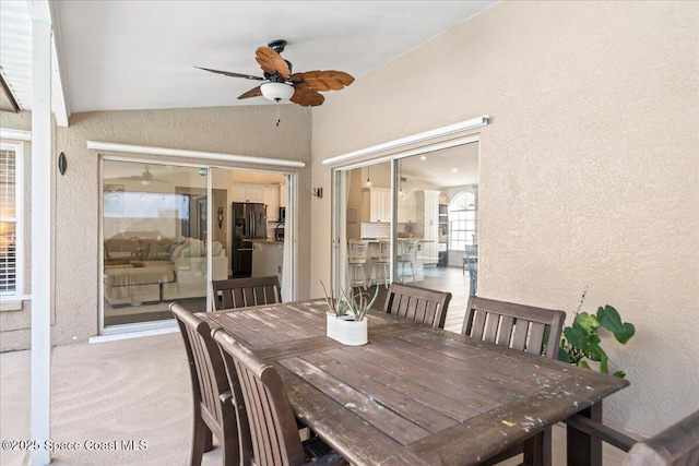 dining space with ceiling fan, light carpet, and vaulted ceiling