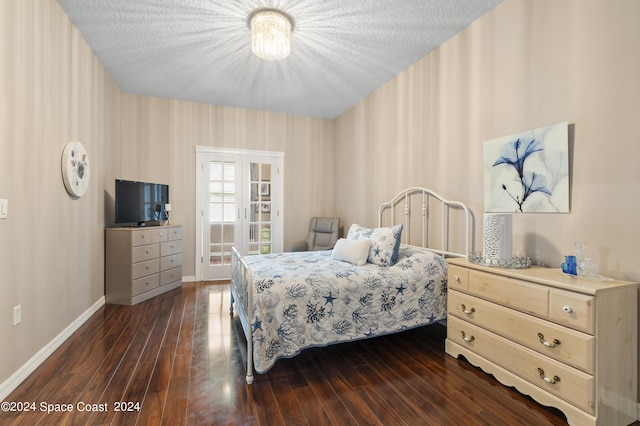 bedroom with french doors, a textured ceiling, and dark wood-type flooring