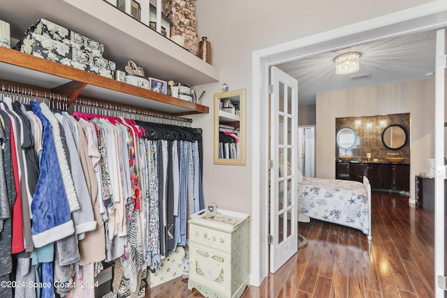 walk in closet featuring a chandelier and dark wood-type flooring