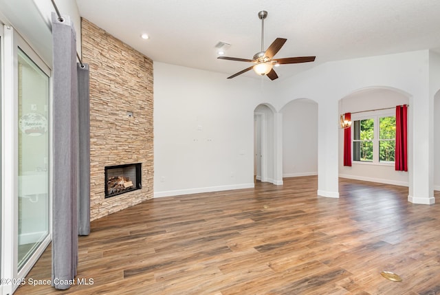 unfurnished living room with a textured ceiling, ceiling fan, a fireplace, and vaulted ceiling