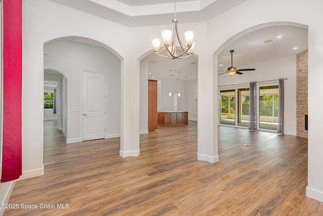 interior space with a fireplace, wood-type flooring, and ceiling fan with notable chandelier