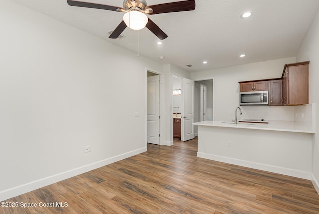 kitchen featuring ceiling fan, sink, kitchen peninsula, wood-type flooring, and a textured ceiling