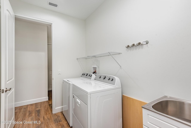 laundry area with dark hardwood / wood-style flooring, washer and dryer, and sink