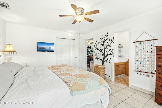 tiled bedroom featuring ceiling fan, a closet, and ensuite bath