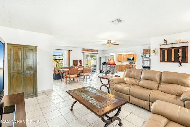 living room with a textured ceiling, ceiling fan, and light tile patterned floors