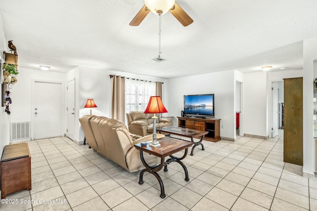 living room with ceiling fan, a textured ceiling, and light tile patterned floors